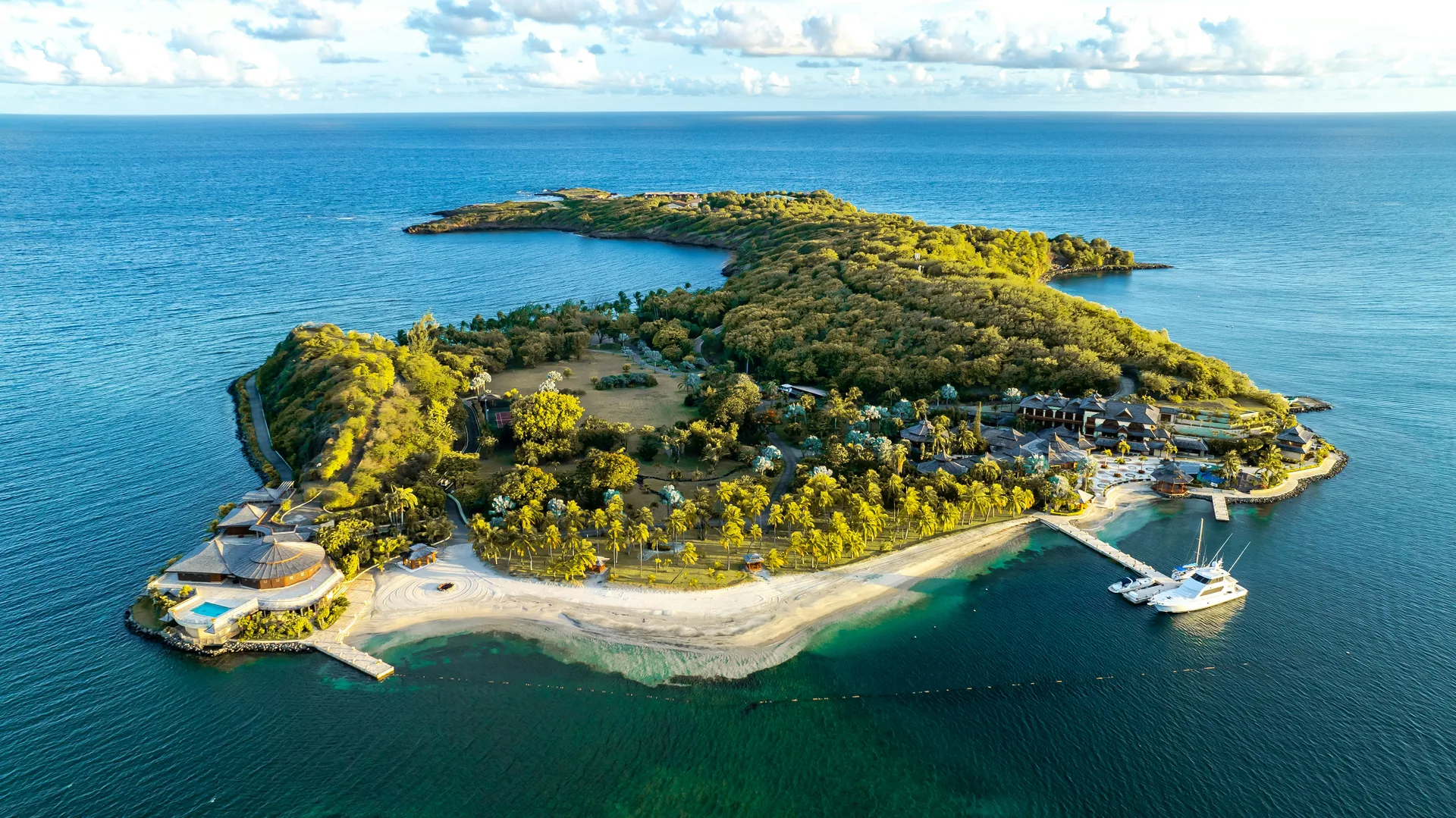Calivigny Island surrounded by turquoise water, with lush gardens, villas and a sandy shore